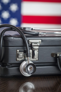 Leather Briefcase and Stethoscope Resting on Table with American Flag Behind.